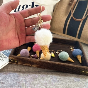 Detailed view of plush ice cream keychain with white fur ball and grey tassel accessory