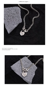 Detail shot showing the silver heart lock pendant with aurora stone on a chunky Cuban chain