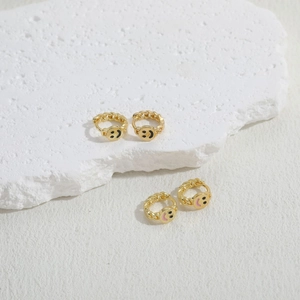 Golden smiling face hoop earrings with chain texture displayed on white stone
