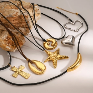 Detail shot of starfish and heart charms on wax cord necklaces against a natural stone background