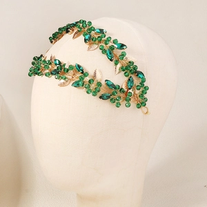 Detail view of retro emerald crystal headband with gold leaves on mannequin head