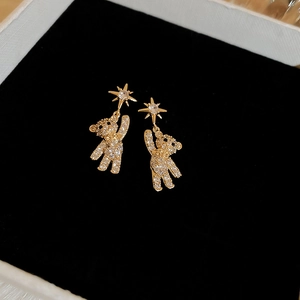 Macro shot of gold star and bear stud earrings with sparkling micro-inlaid rhinestones