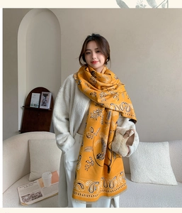 Elegante Frau mit einem gelben Pashmina-Schal mit Paisley-Muster in gemütlicher Umgebung