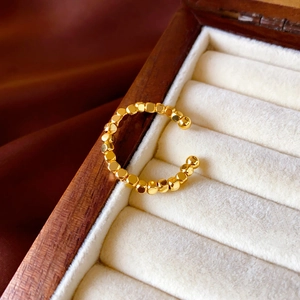 Macro view of gold-plated multifaceted bead ring on white velvet and silk background