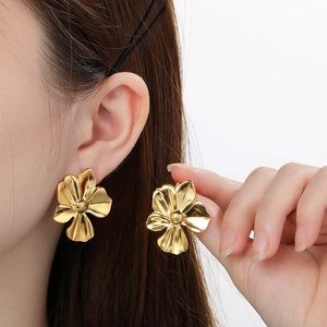Elegant gold ginkgo leaf stainless steel earrings shown on model in detailed close-up
