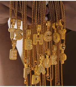 Close-up of gold box chains with zircon-inlaid letter pendants from A to Z