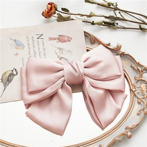 Detail of a large pink satin bow hair clip on a vintage mirror with retro aesthetics