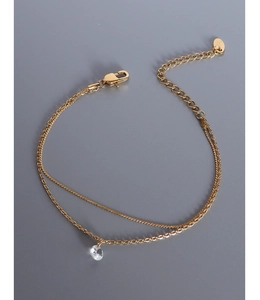 Close-up of double-layer gold chain bracelet with a sparkling round zircon pendant