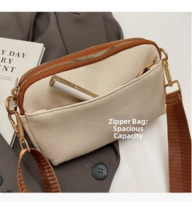 Close-up of beige canvas crossbody bag showing front zipper pocket and gold hardware