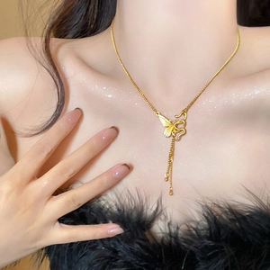 Dettaglio di una collana dorata con ciondolo a farfalla e serpente su una modella