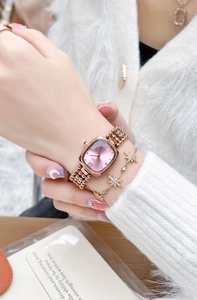 Close-up of rose gold square watch with beaded metal strap worn on a woman wrist