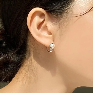 Close-up of elegant pearl hoop earring worn by a model showing minimalist silver details