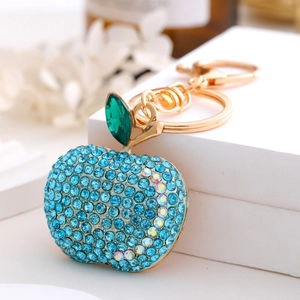 Detail of apple keychain with sparkling blue and rainbow rhinestones on a white stand