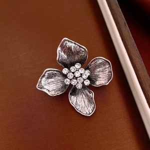 Macro shot of silver vintage flower brooch with textured petals and inlaid white zircons