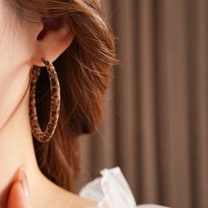 Gros plan de boucles d'oreilles en tissu léopard portées par un mannequin sous la lumière