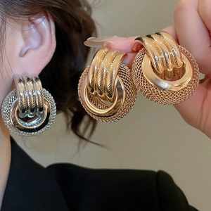 Détail de boucles d'oreilles créoles torsadées en finitions or et argent brillant