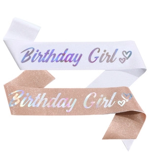 Close-up of white satin and rose gold glitter Birthday Girl sashes with holographic lettering