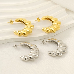 Detailed view of gold and silver irregular C-shaped croissant earrings with wavy texture