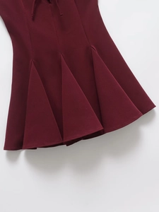 Close-up of wine red pleated hem detail on a stylish flare skirt with woven texture