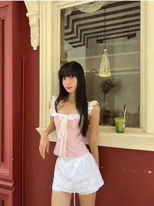 Detailed lace trim on pink plaid crop top with delicate white ribbon bow embellishment