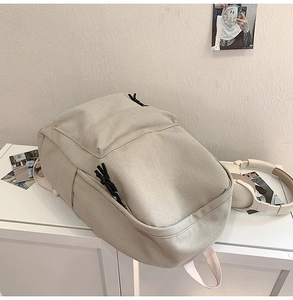 Detail of minimalist beige canvas backpack with black drawstrings on a display shelf