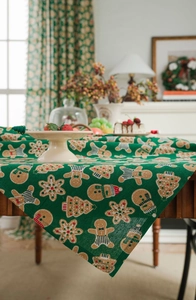 Close-up of green cotton linen tablecloth with gingerbread man and festive holiday patterns