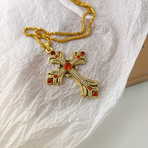 Gros plan détaillé du pendentif croix vintage doré avec strass rouges et blancs