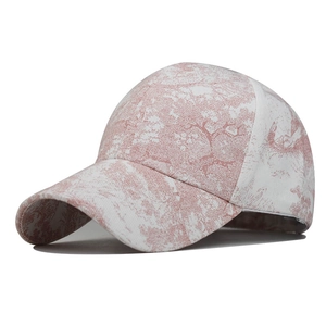 Detailed view of a pink and white floral toile de jouy pattern on a cotton baseball cap