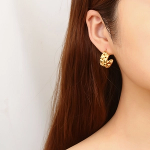 Macro shot of gold-plated C-shape hoop earrings with vintage heart pattern relief