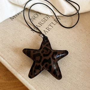 Artistic detail of leopard print star pendant necklace resting on a vintage book page