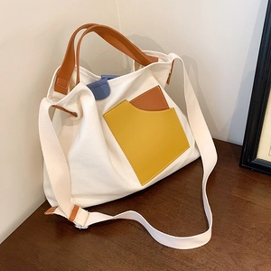 Minimalist beige canvas tote bag with brown handles and colorful geometric leather pockets