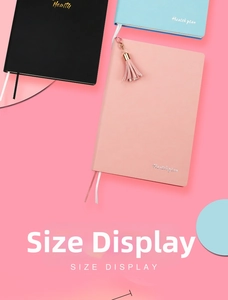 Dettaglio di agende fitness in pelle nera, blu e rosa con nappe dorate e segnalibri coordinati