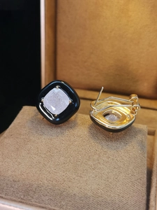 Detailed close-up of square black enamel stud earrings with zircon inlay on brown velvet