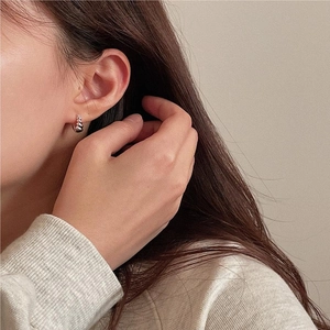 Close-up of minimalist S925 sterling silver twist earring worn by a model