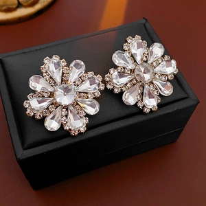 Detailed view of flower-shaped earrings with crystal petals on a black jewelry box
