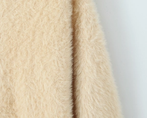Macro detail of soft beige mohair fabric texture on long hooded cardigan sweater
