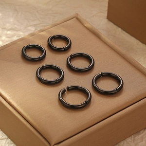 Six clips d'oreille noirs en acier inoxydable sur un écrin à bijoux de couleur bronze