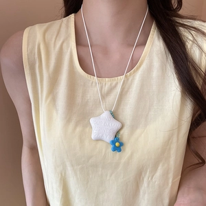 Dettaglio del ciondolo a stella con testo creativo e fiore blu su una collana bianca