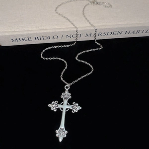 Macro shot of a silver cross pendant necklace with diamonds on black velvet background