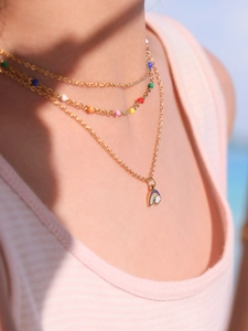 Gros plan du collier arc-en-ciel doré avec perles colorées porté au coucher du soleil