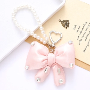 Detailed view of a pink satin bow keychain with sparkling rhinestones and pearl chain