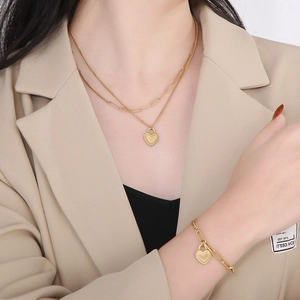 Golden double-layered heart lock necklace and bracelet set worn by a female model