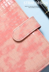Detail of pink croc-embossed A6 binder cover with secure magnetic strap closure