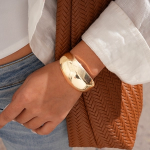 Polished 18k gold-plated cuff bracelet shown on model with lifestyle accessories