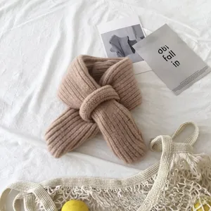 Detail of soft ribbed knit baby scarf in beige, styled with aesthetic props on fabric