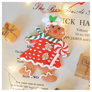 Close-up of clay gingerbread man ornament with red skirt and candy cane on festive background