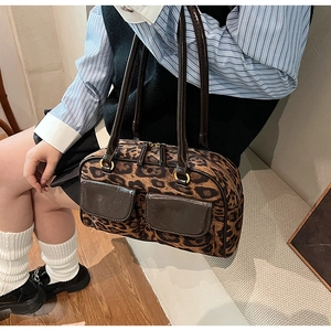 Detail of leopard print shoulder bag with two brown leather front pockets and gold zippers