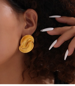 Detail of gold spiral drop earring featuring intricate textured layers and artistic design