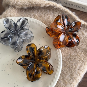Three leopard print flower hair claws in amber and grey resin on a ceramic plate