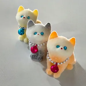 Detail of three cute flocked cat squishy toys with pearl necklaces and colorful bells